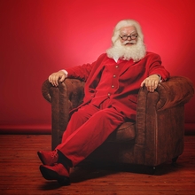 Santa in red suit sitting on a chair.